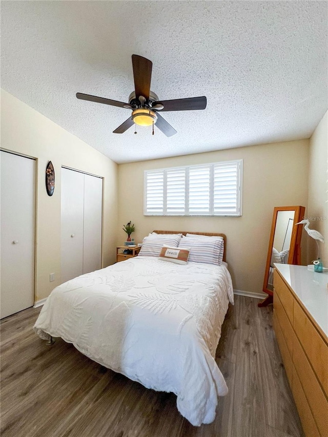 659 Garland Cir, Indian Rocks Beach, FL 33785 - bedroom featuring wood finished floors, a textured ceiling, two closets, and a ceiling fan