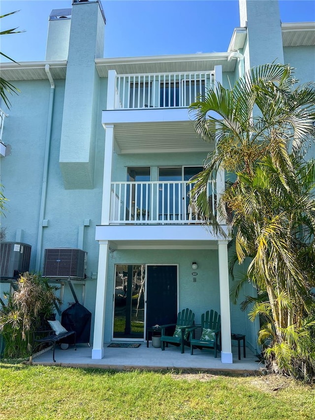 659 Garland Cir, Indian Rocks Beach, FL 33785 - back of house featuring a balcony, a patio, stucco siding, and a chimney