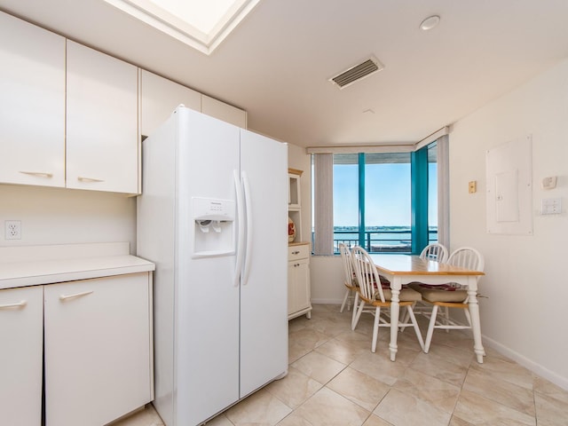 1520 Gulf Blvd Unit 1505, Clearwater Beach, FL 33767 - kitchen featuring white refrigerator with ice dispenser, white cabinets, light countertops, baseboards, and a water view