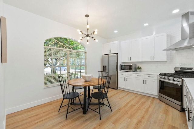970 Ridgewood Ter, Tarpon Springs, FL 34689 - kitchen with wall chimney range hood, appliances with stainless steel finishes, backsplash, light wood-style flooring, and light countertops
