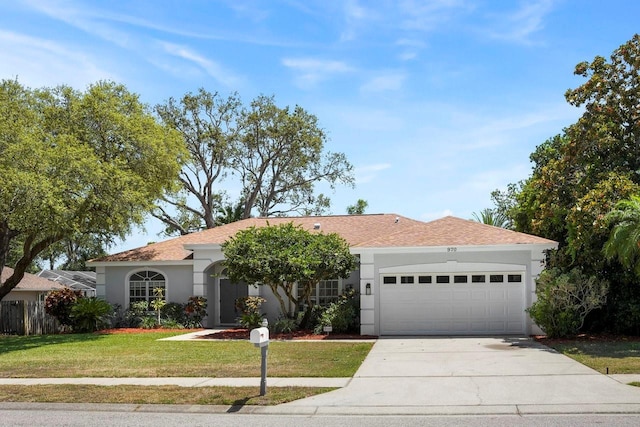 970 Ridgewood Ter, Tarpon Springs, FL 34689 - view of front facade with a garage, a front lawn, stucco siding, driveway, and roof with shingles