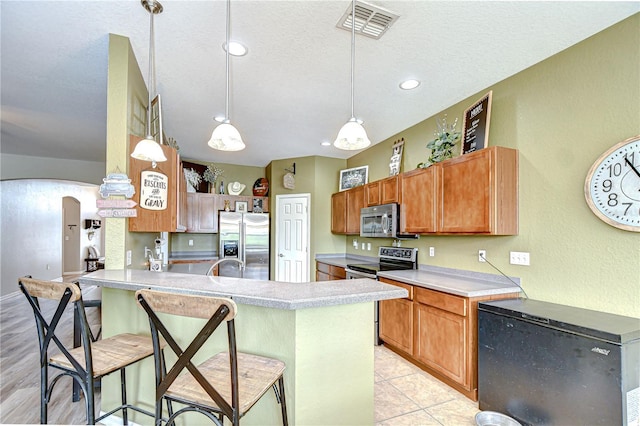 6519 Twin Bridges Dr, Zephyrhills, FL 33541 - kitchen featuring stainless steel appliances, a peninsula, a textured ceiling, light countertops, and arched walkways
