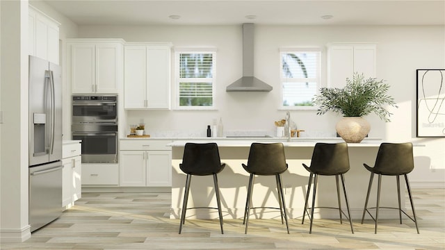 18154 Serene Lake Loop, Lutz, FL 33548 - kitchen featuring wall chimney exhaust hood, appliances with stainless steel finishes, an island with sink, light countertops, and white cabinets