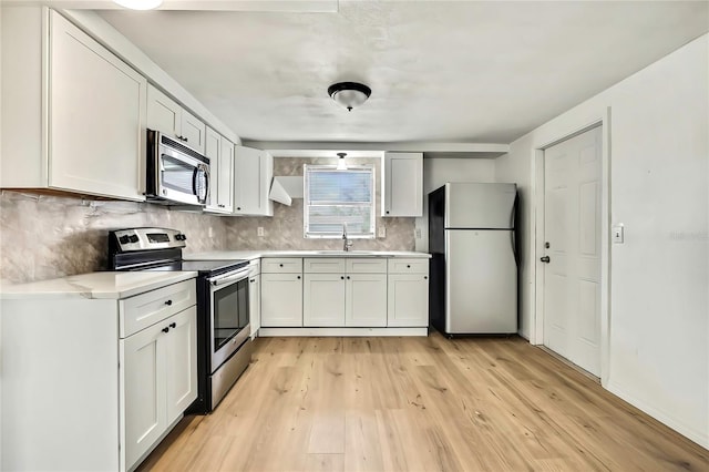 11130 White Oak Ln, Port Richey, FL 34668 - kitchen with stainless steel appliances, a sink, light wood-style floors, and white cabinets