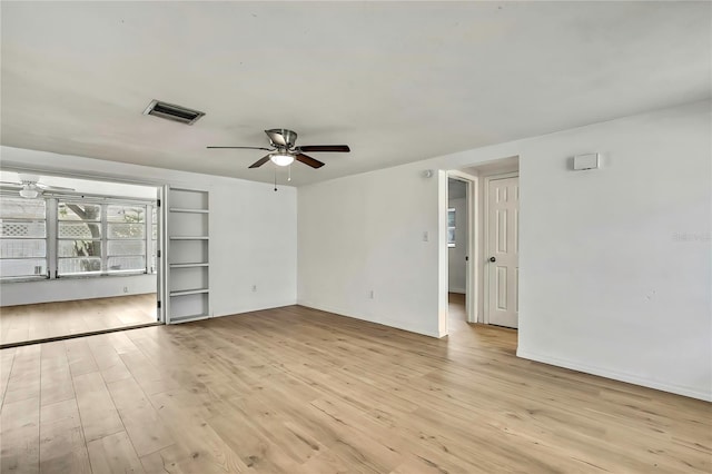 11130 White Oak Ln, Port Richey, FL 34668 - spare room featuring a ceiling fan, light wood-style flooring, baseboards, and built in shelves