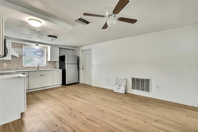 11130 White Oak Ln, Port Richey, FL 34668 - kitchen with stainless steel appliances, light countertops, ceiling fan, light wood finished floors, and decorative backsplash