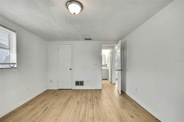 11130 White Oak Ln, Port Richey, FL 34668 - unfurnished bedroom with light wood-style floors, baseboards, and washer / clothes dryer
