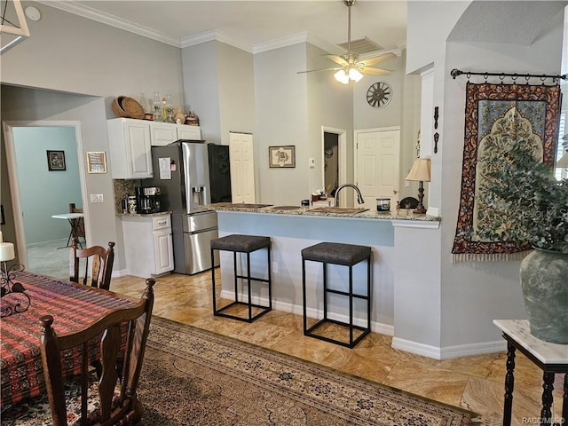 4755 N El Camino Dr, Beverly Hills, FL 34465 - kitchen with stainless steel fridge, a peninsula, a breakfast bar area, white cabinetry, and ceiling fan