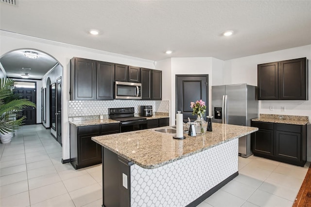 10233 Opaline Sky Pl, Riverview, FL 33578 - kitchen with appliances with stainless steel finishes, light stone countertops, arched walkways, a sink, and tasteful backsplash