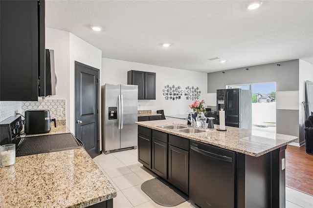 10233 Opaline Sky Pl, Riverview, FL 33578 - kitchen featuring appliances with stainless steel finishes, a sink, a kitchen island with sink, decorative backsplash, and light stone countertops