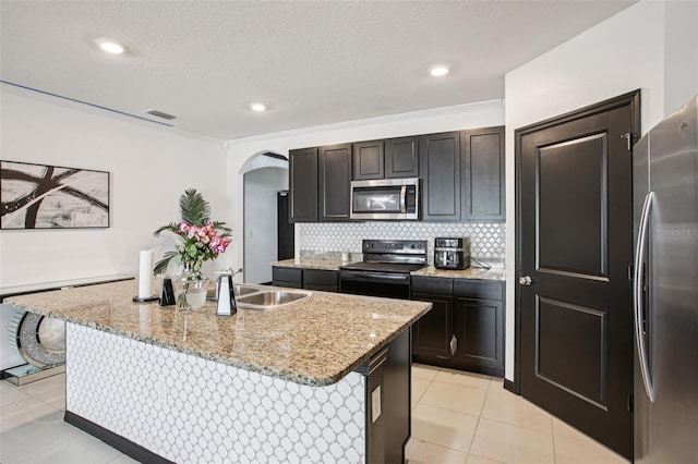 10233 Opaline Sky Pl, Riverview, FL 33578 - kitchen featuring appliances with stainless steel finishes, arched walkways, a sink, light tile patterned floors, and light stone countertops