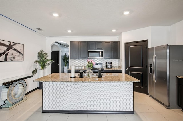 10233 Opaline Sky Pl, Riverview, FL 33578 - kitchen with appliances with stainless steel finishes, arched walkways, light stone countertops, backsplash, and light tile patterned floors