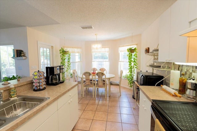 2826 Martha Ln, Land O Lakes, FL 34639 - kitchen with black microwave, a sink, a chandelier, light countertops, and light tile patterned floors