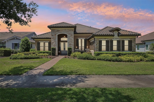 14715 Fishhawk Preserve Dr, Lithia, FL 33547 - mediterranean / spanish-style house featuring stone siding, a tiled roof, stucco siding, and a yard