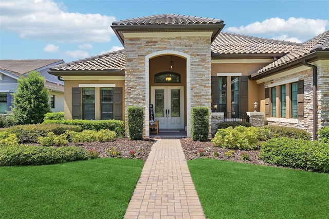 14715 Fishhawk Preserve Dr, Lithia, FL 33547 - view of exterior entry with stone siding, french doors, a yard, and stucco siding