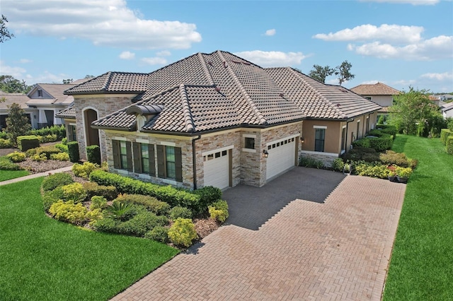 14715 Fishhawk Preserve Dr, Lithia, FL 33547 - mediterranean / spanish-style house featuring stone siding, an attached garage, decorative driveway, and a front yard