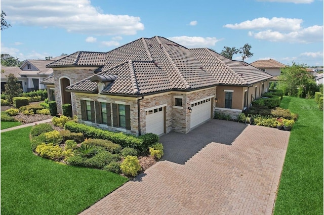 14715 Fishhawk Preserve Dr, Lithia, FL 33547 - mediterranean / spanish-style house with stone siding, a garage, decorative driveway, and a front yard