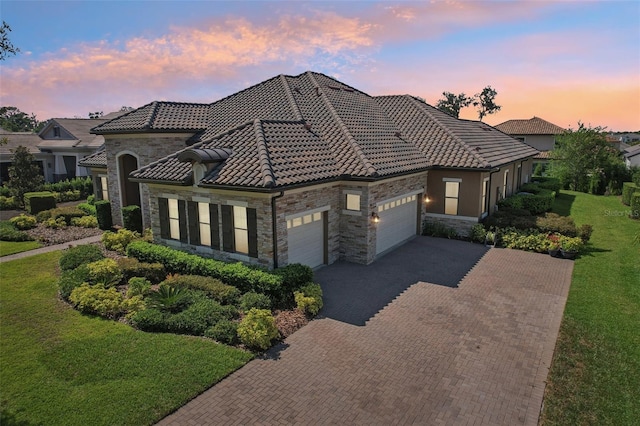 14715 Fishhawk Preserve Dr, Lithia, FL 33547 - mediterranean / spanish-style home featuring stone siding, an attached garage, decorative driveway, a lawn, and a tile roof