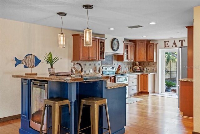 4301 S Lockwood Ridge Rd, Sarasota, FL 34231 - kitchen with electric range, light wood-style floors, a kitchen breakfast bar, wine cooler, and backsplash