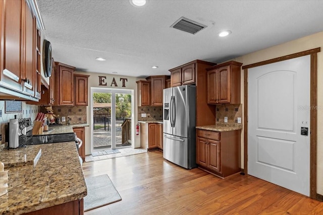 4301 S Lockwood Ridge Rd, Sarasota, FL 34231 - kitchen with stainless steel fridge, backsplash, light wood-type flooring, light stone countertops, and recessed lighting