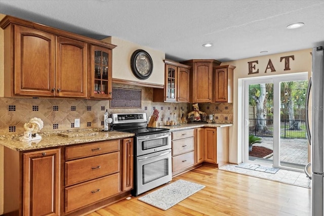 4301 S Lockwood Ridge Rd, Sarasota, FL 34231 - kitchen with stainless steel appliances, light wood-style floors, light stone counters, glass insert cabinets, and decorative backsplash