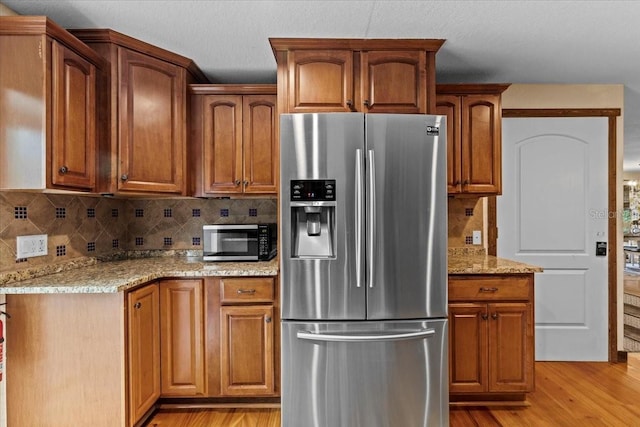 4301 S Lockwood Ridge Rd, Sarasota, FL 34231 - kitchen with appliances with stainless steel finishes, light wood finished floors, light stone counters, tasteful backsplash, and brown cabinets