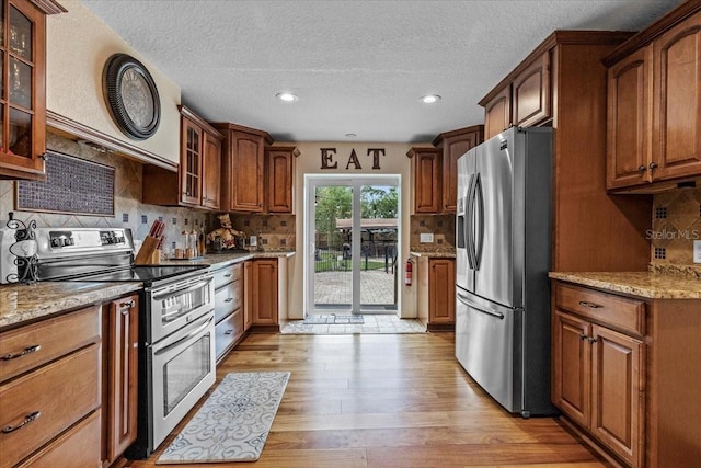 4301 S Lockwood Ridge Rd, Sarasota, FL 34231 - kitchen with appliances with stainless steel finishes, light stone countertops, light wood-style floors, a textured ceiling, and glass insert cabinets