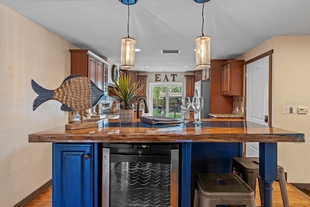 4301 S Lockwood Ridge Rd, Sarasota, FL 34231 - kitchen featuring beverage cooler, freestanding refrigerator, light wood finished floors, baseboards, and a breakfast bar
