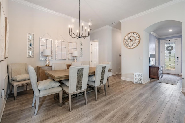 4620 Ballast Crest Cv, Land O Lakes, FL 34638 - dining space featuring arched walkways, light wood-type flooring, a chandelier, and ornamental molding