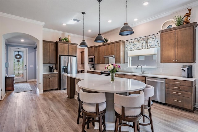 4620 Ballast Crest Cv, Land O Lakes, FL 34638 - kitchen with appliances with stainless steel finishes, arched walkways, a kitchen breakfast bar, light countertops, and crown molding
