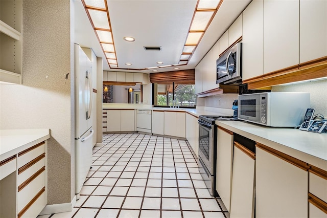 707 Warren Rd, Lutz, FL 33548 - kitchen with appliances with stainless steel finishes, light countertops, white cabinetry, recessed lighting, and light tile patterned flooring