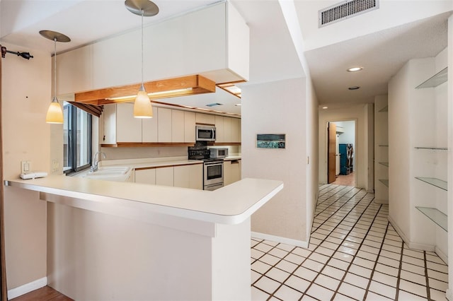 707 Warren Rd, Lutz, FL 33548 - kitchen with stainless steel appliances, a sink, light countertops, hanging light fixtures, and a peninsula