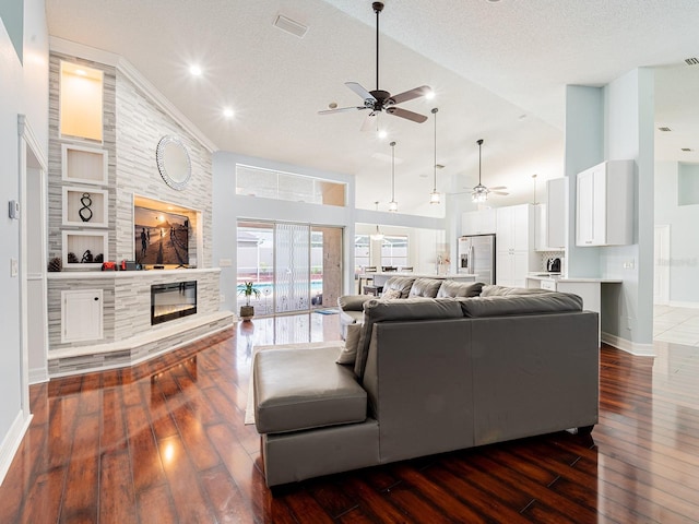 382 Florian Way, Spring Hill, FL 34609 - living room featuring ceiling fan, dark wood finished floors, baseboards, a stone fireplace, and a textured ceiling