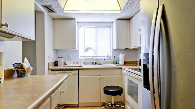 3534 Lake Bayshore Dr Unit 118, Bradenton, FL 34205 - kitchen featuring white appliances, light countertops, a sink, and a textured ceiling