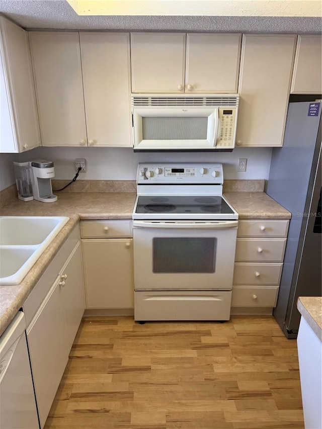 3534 Lake Bayshore Dr Unit 118, Bradenton, FL 34205 - kitchen featuring white appliances, light wood-style flooring, a sink, and light countertops