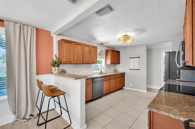 504 7th Ave SW, Largo, FL 33770 - kitchen with stainless steel appliances, a sink, a textured ceiling, brown cabinets, and decorative backsplash