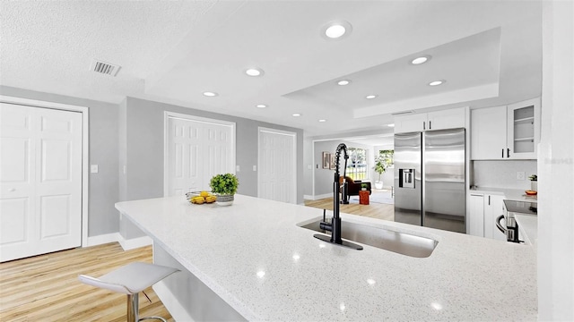 829 Riverside Dr, Tarpon Springs, FL 34689 - kitchen featuring appliances with stainless steel finishes, a tray ceiling, light stone countertops, white cabinets, and recessed lighting