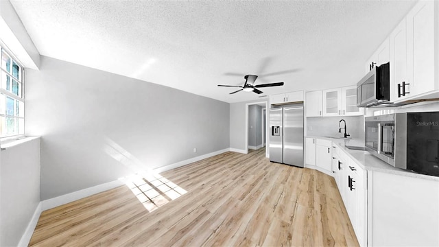 829 Riverside Dr, Tarpon Springs, FL 34689 - kitchen featuring appliances with stainless steel finishes, a sink, a textured ceiling, baseboards, and light wood-style floors