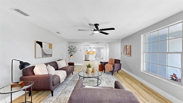 829 Riverside Dr, Tarpon Springs, FL 34689 - living room with a textured ceiling, light wood-style floors, a ceiling fan, and baseboards