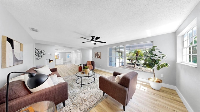 829 Riverside Dr, Tarpon Springs, FL 34689 - living room featuring a textured ceiling, light wood-style flooring, a ceiling fan, and baseboards