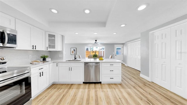 829 Riverside Dr, Tarpon Springs, FL 34689 - kitchen with stainless steel appliances, a peninsula, light wood-style floors, recessed lighting, and light countertops