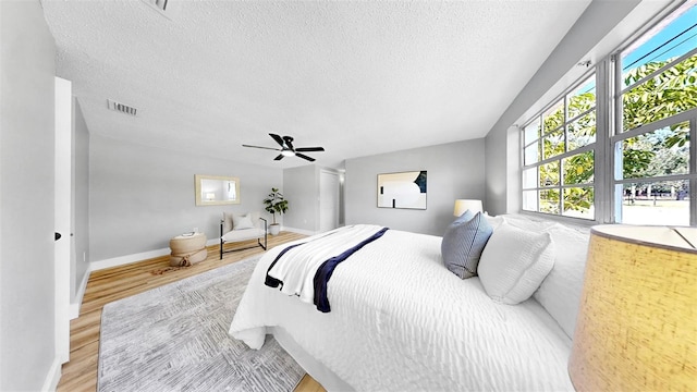 829 Riverside Dr, Tarpon Springs, FL 34689 - bedroom with light wood-style floors, multiple windows, a textured ceiling, a ceiling fan, and baseboards