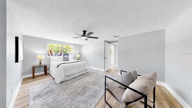 829 Riverside Dr, Tarpon Springs, FL 34689 - bedroom with light wood-style floors, baseboards, ceiling fan, and a textured ceiling