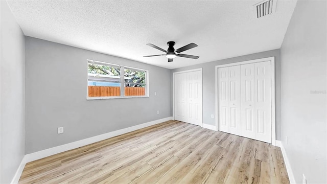 829 Riverside Dr, Tarpon Springs, FL 34689 - unfurnished bedroom featuring multiple closets, a textured ceiling, wood finished floors, baseboards, and a ceiling fan