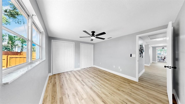 829 Riverside Dr, Tarpon Springs, FL 34689 - unfurnished bedroom featuring multiple closets, baseboards, light wood-type flooring, ceiling fan, and a textured ceiling