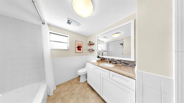 829 Riverside Dr, Tarpon Springs, FL 34689 - full bathroom featuring tile walls, vanity, a wainscoted wall, toilet, and tile patterned flooring