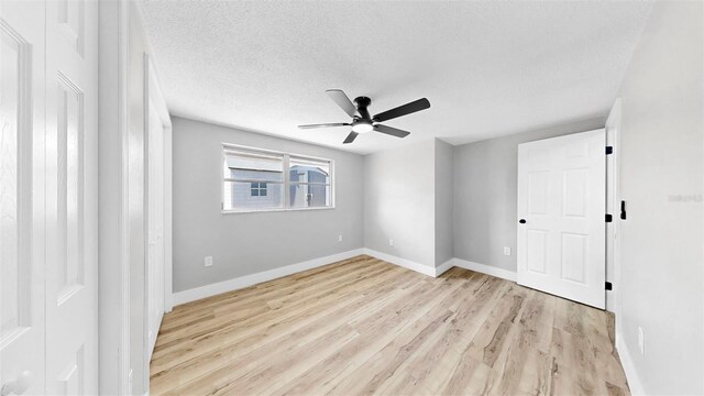 829 Riverside Dr, Tarpon Springs, FL 34689 - empty room with ceiling fan, light wood-type flooring, baseboards, and a textured ceiling