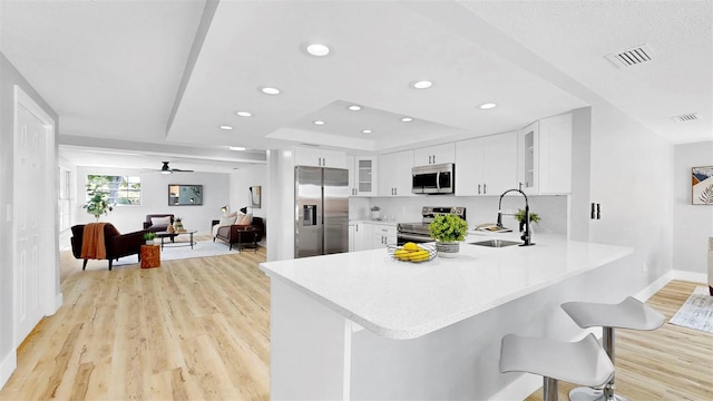 829 Riverside Dr, Tarpon Springs, FL 34689 - kitchen with stainless steel appliances, a sink, light wood-type flooring, light countertops, and glass insert cabinets