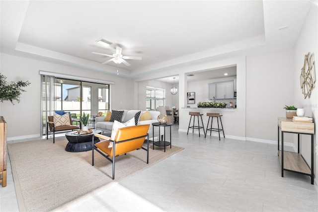 6563 Ryestone Way, Wesley Chapel, FL 33545 - living room featuring a raised ceiling, a ceiling fan, and baseboards