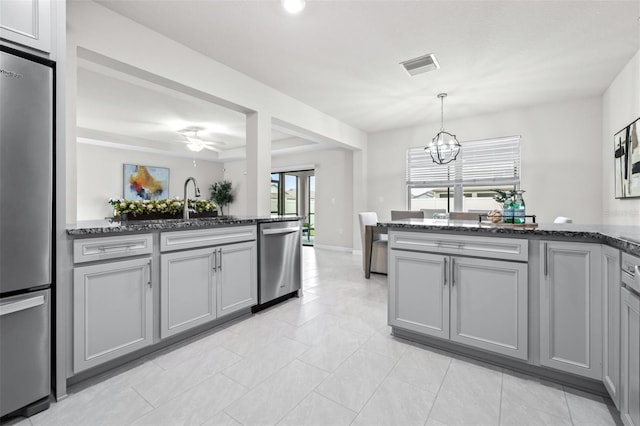 6563 Ryestone Way, Wesley Chapel, FL 33545 - kitchen featuring appliances with stainless steel finishes, gray cabinets, a chandelier, dark stone counters, and a peninsula